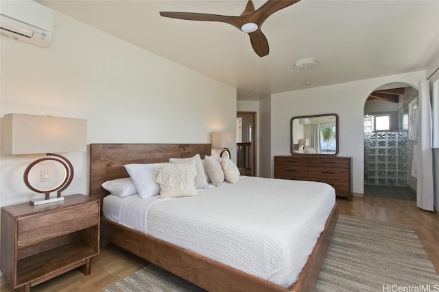 bedroom with a wall mounted AC, ceiling fan, and light hardwood / wood-style flooring