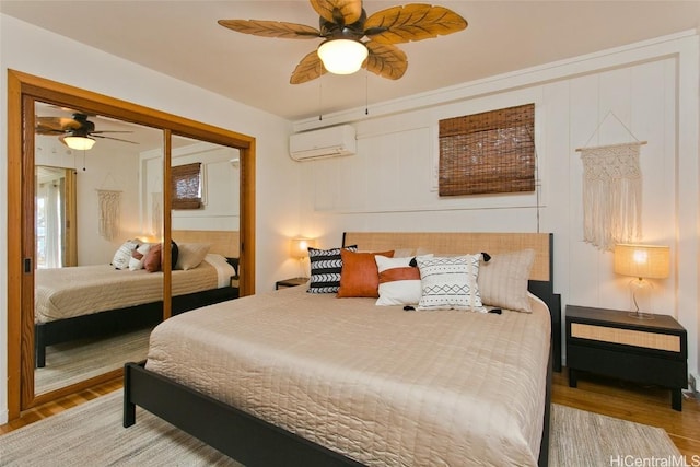 bedroom with ceiling fan, a closet, wood-type flooring, and a wall mounted AC