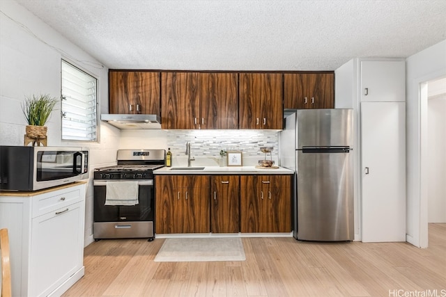 kitchen featuring exhaust hood, decorative backsplash, stainless steel appliances, and light wood-type flooring