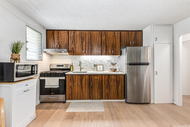 1145 Davenport St Unit 206, Honolulu, HI 96822 - kitchen with stainless steel appliances, under cabinet range hood, light wood-style flooring, a textured ceiling, and light countertops