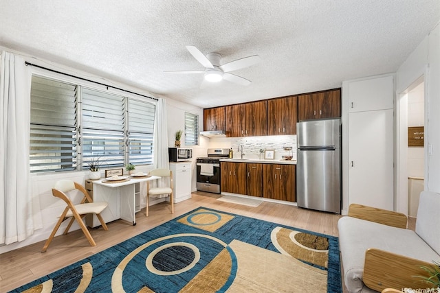 1145 Davenport St Unit 206, Honolulu, HI 96822 - kitchen with appliances with stainless steel finishes, light wood finished floors, a ceiling fan, a textured ceiling, and ventilation hood
