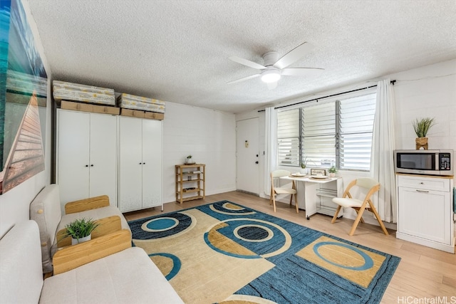 sitting room featuring light hardwood / wood-style floors, a textured ceiling, and ceiling fan