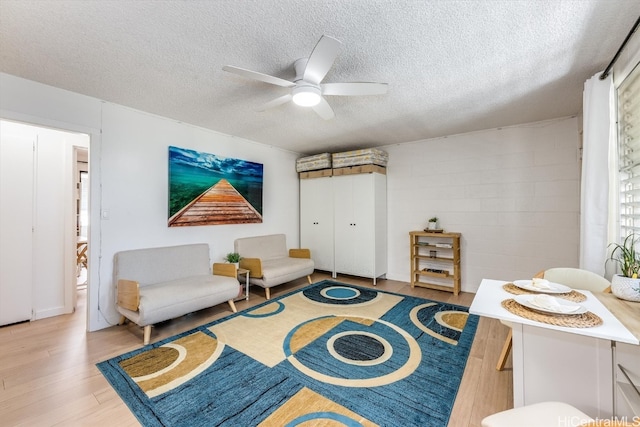 living area featuring light hardwood / wood-style floors, a textured ceiling, and ceiling fan