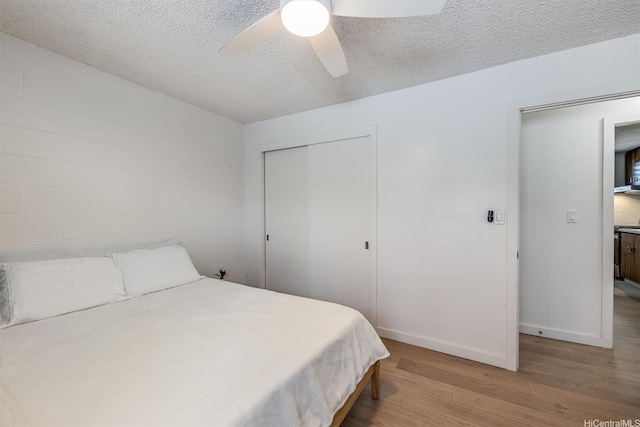1145 Davenport St Unit 206, Honolulu, HI 96822 - bedroom with light wood-style flooring, a closet, a textured ceiling, a ceiling fan, and concrete block wall