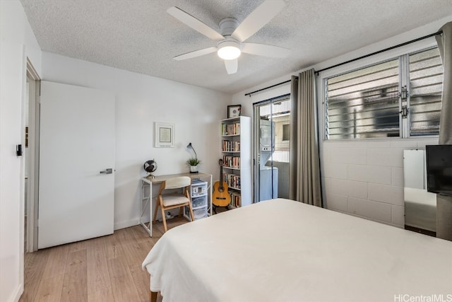 bedroom with a textured ceiling, light hardwood / wood-style floors, and ceiling fan