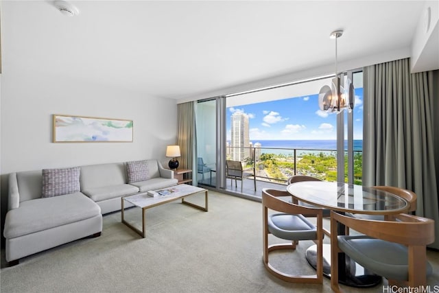 living room featuring carpet flooring, floor to ceiling windows, a water view, and an inviting chandelier