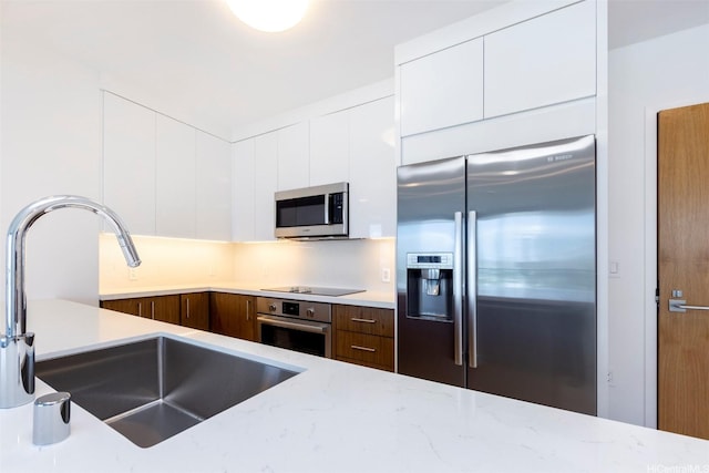 kitchen with stainless steel appliances, white cabinetry, a sink, and modern cabinets