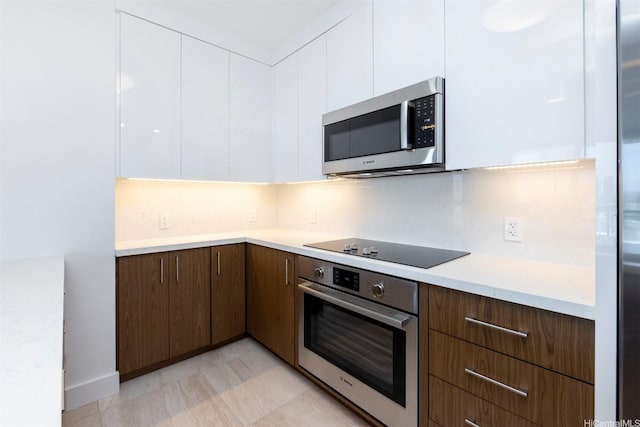 kitchen with appliances with stainless steel finishes, modern cabinets, dark brown cabinets, light countertops, and white cabinetry