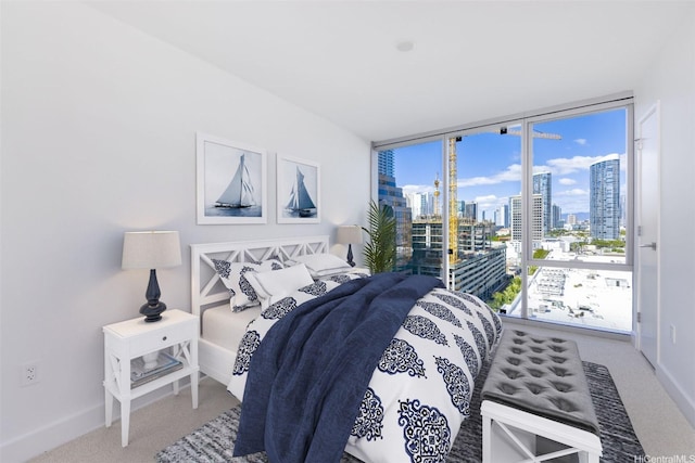 bedroom featuring a view of city, baseboards, carpet, and expansive windows