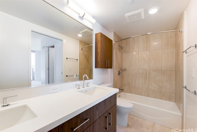 full bathroom with tile patterned flooring, vanity, tiled shower / bath combo, and toilet