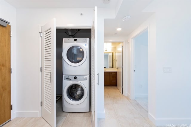 laundry area featuring light tile patterned floors and stacked washing maching and dryer