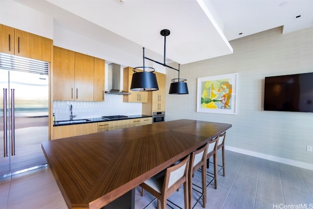 kitchen with sink, tasteful backsplash, decorative light fixtures, appliances with stainless steel finishes, and wall chimney range hood