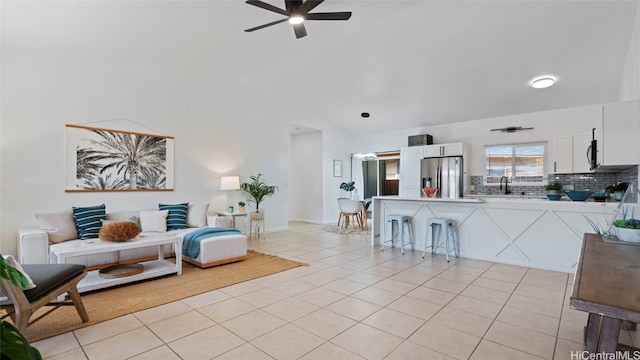 living room featuring ceiling fan, light tile patterned flooring, and vaulted ceiling