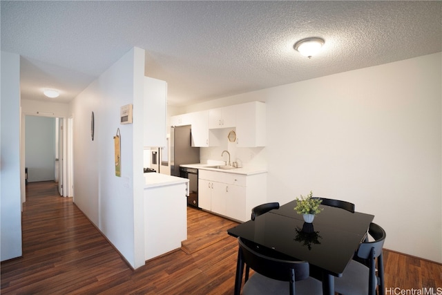 kitchen with a textured ceiling, white cabinetry, sink, and dark hardwood / wood-style flooring