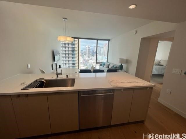 kitchen with sink, hanging light fixtures, stainless steel dishwasher, kitchen peninsula, and hardwood / wood-style floors