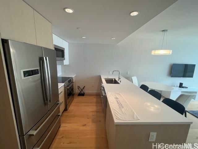 kitchen with recessed lighting, stainless steel appliances, a sink, white cabinetry, and light wood-type flooring