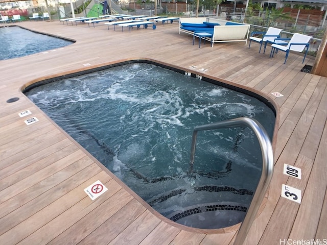 view of pool featuring a community hot tub and a deck