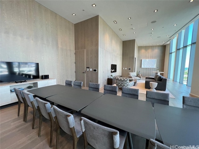 dining area with a towering ceiling, a wall of windows, and wood-type flooring