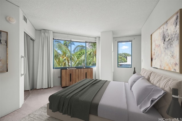 bedroom with a textured ceiling and light colored carpet