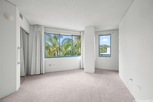 spare room featuring light carpet and a textured ceiling