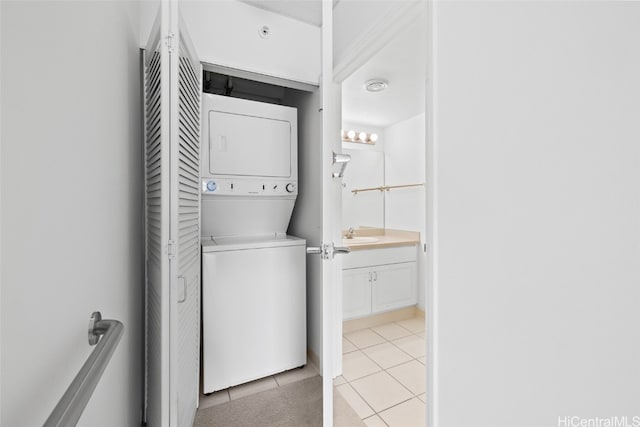 laundry area with sink, stacked washer / drying machine, and light tile patterned floors