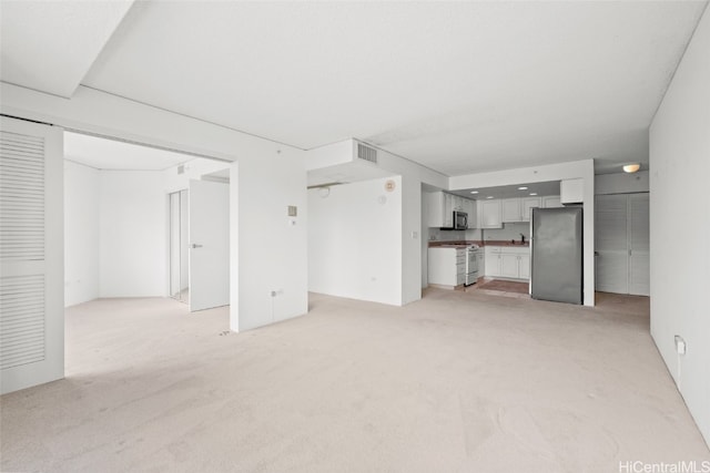 unfurnished living room featuring sink and light carpet