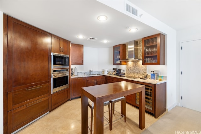 kitchen with wall chimney range hood, backsplash, sink, appliances with stainless steel finishes, and light stone counters