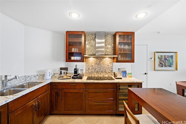 kitchen featuring decorative backsplash, wall chimney range hood, black electric cooktop, sink, and light stone counters