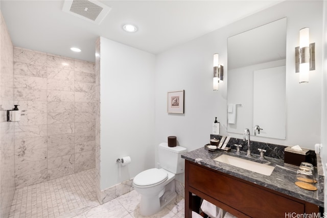 bathroom with vanity, toilet, and a tile shower