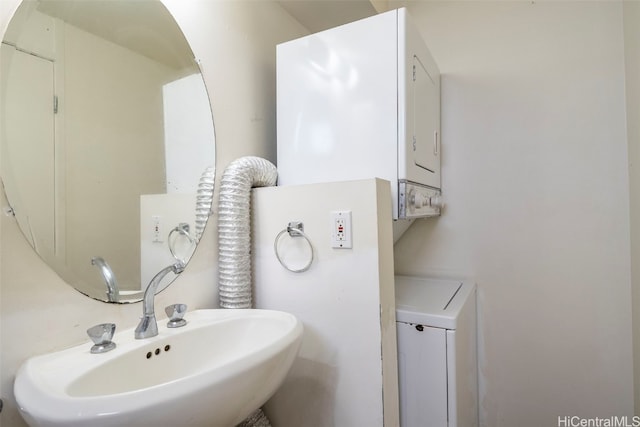 bathroom featuring stacked washing maching and dryer and sink