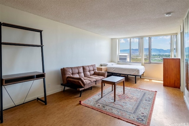 bedroom with a mountain view, wood-type flooring, and a textured ceiling