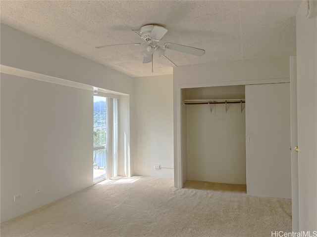 unfurnished bedroom featuring a closet, ceiling fan, light carpet, and a textured ceiling