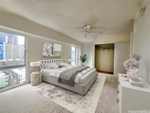 carpeted bedroom with multiple windows, a textured ceiling, a closet, and ceiling fan