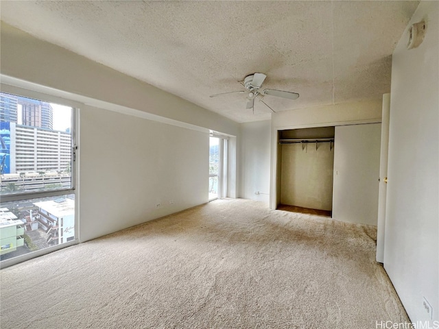 unfurnished bedroom with light carpet, a closet, a textured ceiling, and ceiling fan