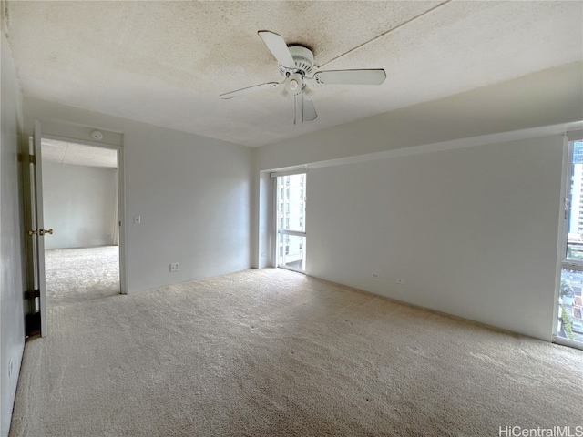 empty room with ceiling fan, light carpet, a textured ceiling, and plenty of natural light