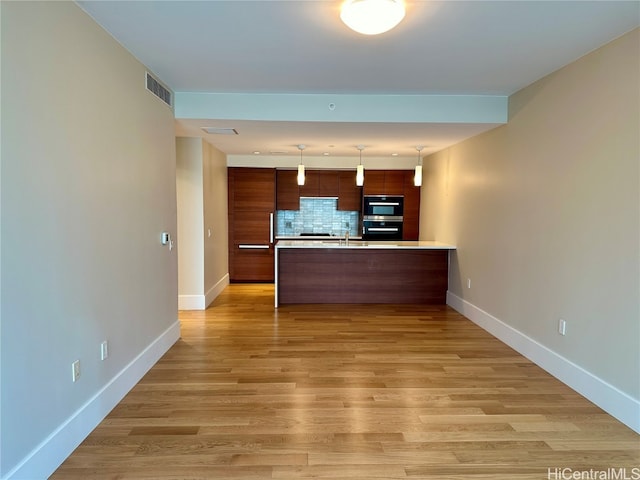 kitchen with light hardwood / wood-style flooring, backsplash, decorative light fixtures, and sink