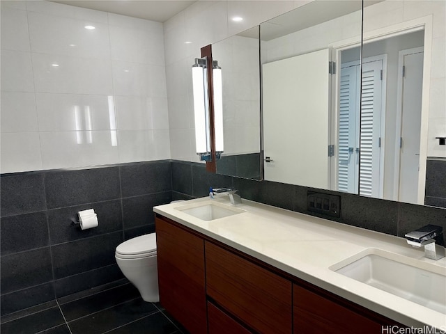 bathroom with vanity, toilet, tile patterned floors, and tile walls