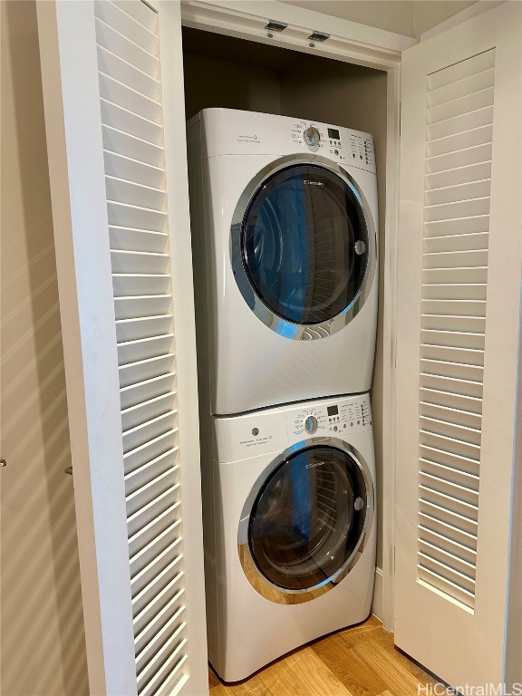 washroom with stacked washer and dryer and light wood-type flooring