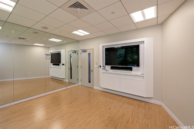 spare room with a drop ceiling and light wood-type flooring