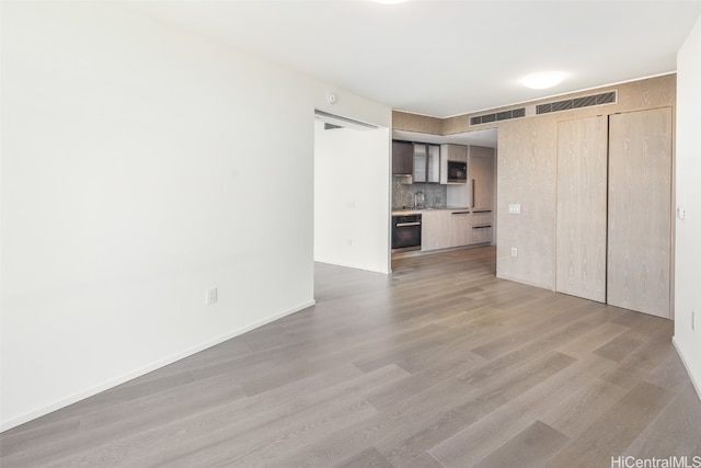 unfurnished living room featuring sink and light hardwood / wood-style floors