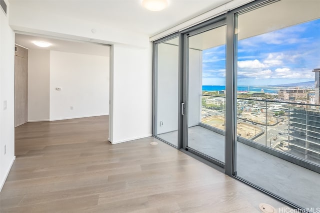 empty room featuring expansive windows, hardwood / wood-style flooring, and a water view