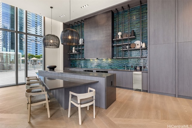 bar featuring a wall of windows, decorative backsplash, sink, and hanging light fixtures