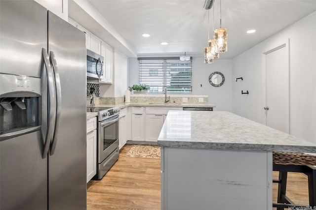 2355 Ala Wai Blvd Unit 201, Honolulu, HI 96815 - kitchen with stainless steel appliances, a sink, a kitchen island, light wood-style floors, and a breakfast bar area