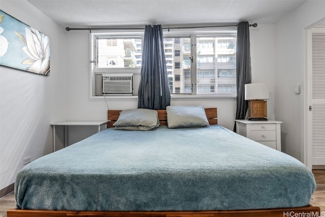 bedroom with wood-type flooring, a textured ceiling, and cooling unit