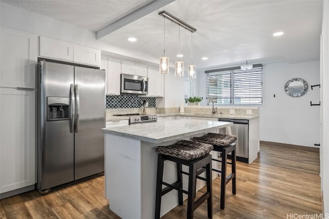 kitchen featuring appliances with stainless steel finishes, a center island, hardwood / wood-style floors, and white cabinets