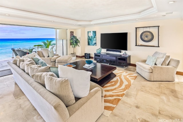 living room featuring ornamental molding, a water view, and a raised ceiling