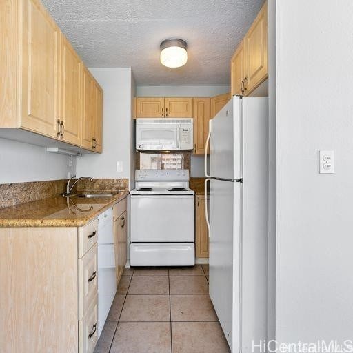 kitchen with white appliances, sink, a textured ceiling, light tile patterned floors, and light brown cabinets