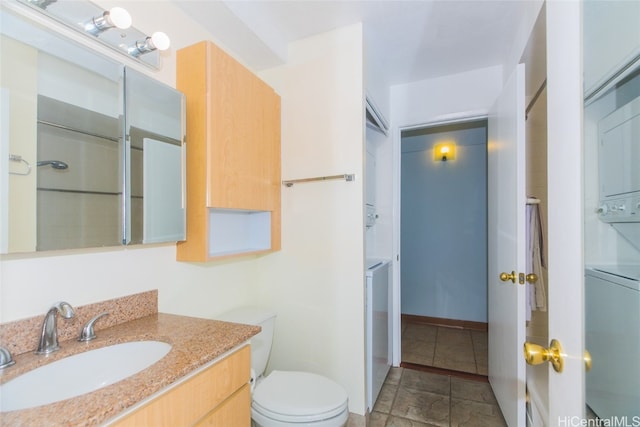 bathroom featuring stacked washer / drying machine, vanity, and toilet