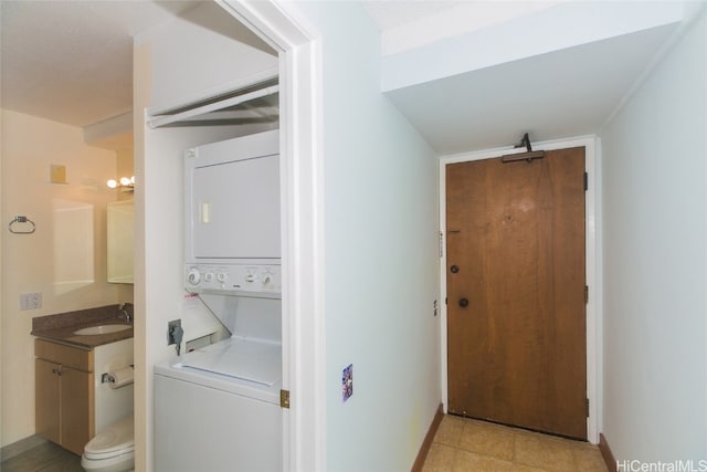 laundry area with stacked washer / drying machine and sink