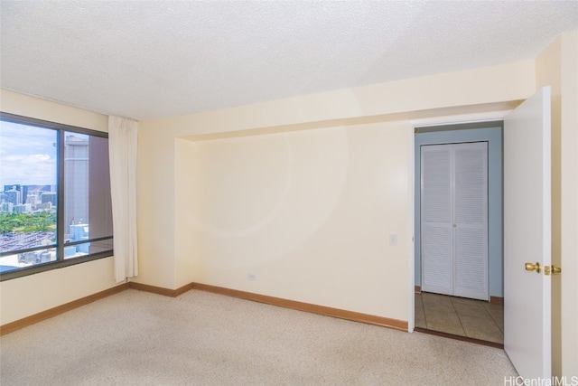 carpeted empty room featuring a textured ceiling